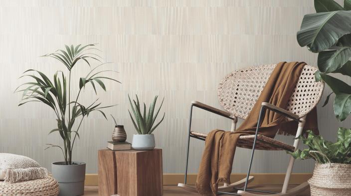 rocking chair and lots of plants in front of creme coloured wallpaper with grafic stripe design