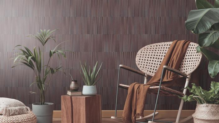 rocking chair and lots of plants in front of brown wallpaper with grafic stripe design