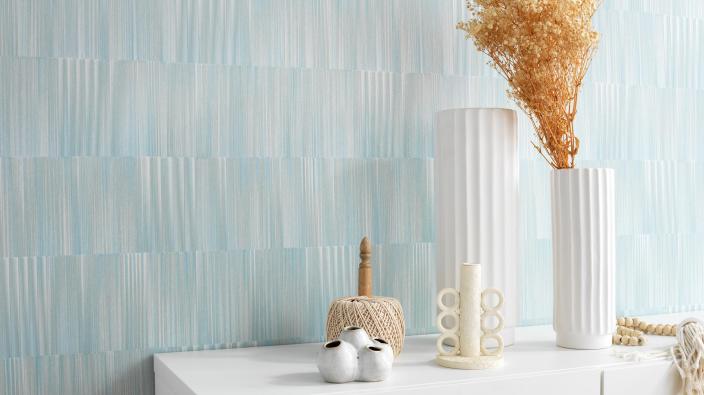 bright lightblue wallpaper with stripe pattern and sideboard with white vase