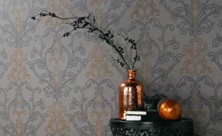 Tapete im Ethno-Look in Grau und Bronze mit modernem Ornament, Vase in Kupfer auf Beistelltisch