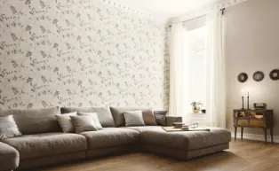 Wohnzimmer mit Couchlandschaft in Taupe, Tapete mit Blattmotiv